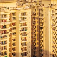 A striking urban scene showcasing modern high-rise residential towers set against a dramatic, moody sky in Noida, India. This dynamic composition captures the essence of rapid urban development, city life, and architectural growth in one of India’s fastest-growing metropolitan regions